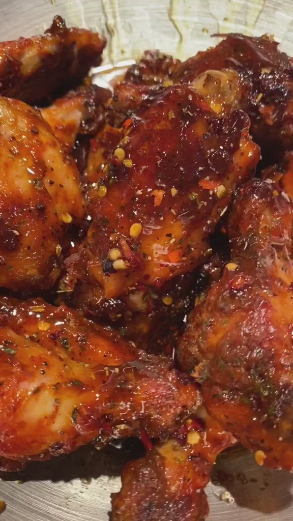 This may contain: some chicken wings are sitting on a plate with sauce and seasoning sprinkles