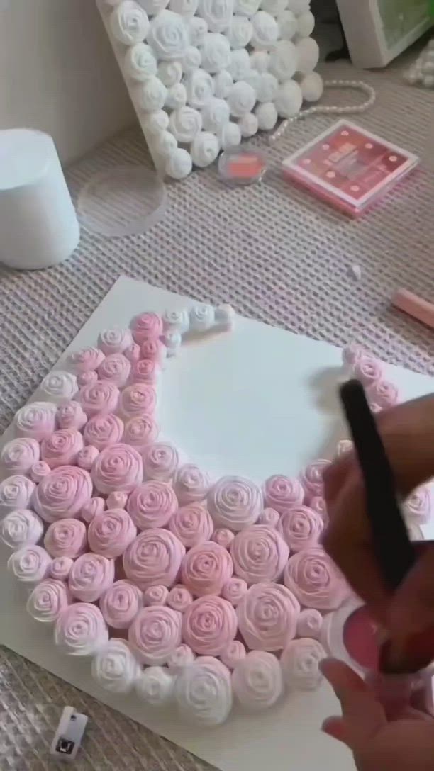 This may contain: someone is decorating a heart shaped cake with pink icing and roses on it