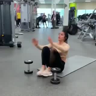 This may contain: a woman is laying on the floor in a gym with dumbbells and exercise equipment