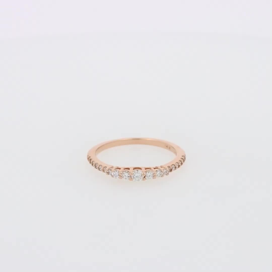 This may contain: a rose gold ring with five diamonds on the top and bottom, sitting on a white surface