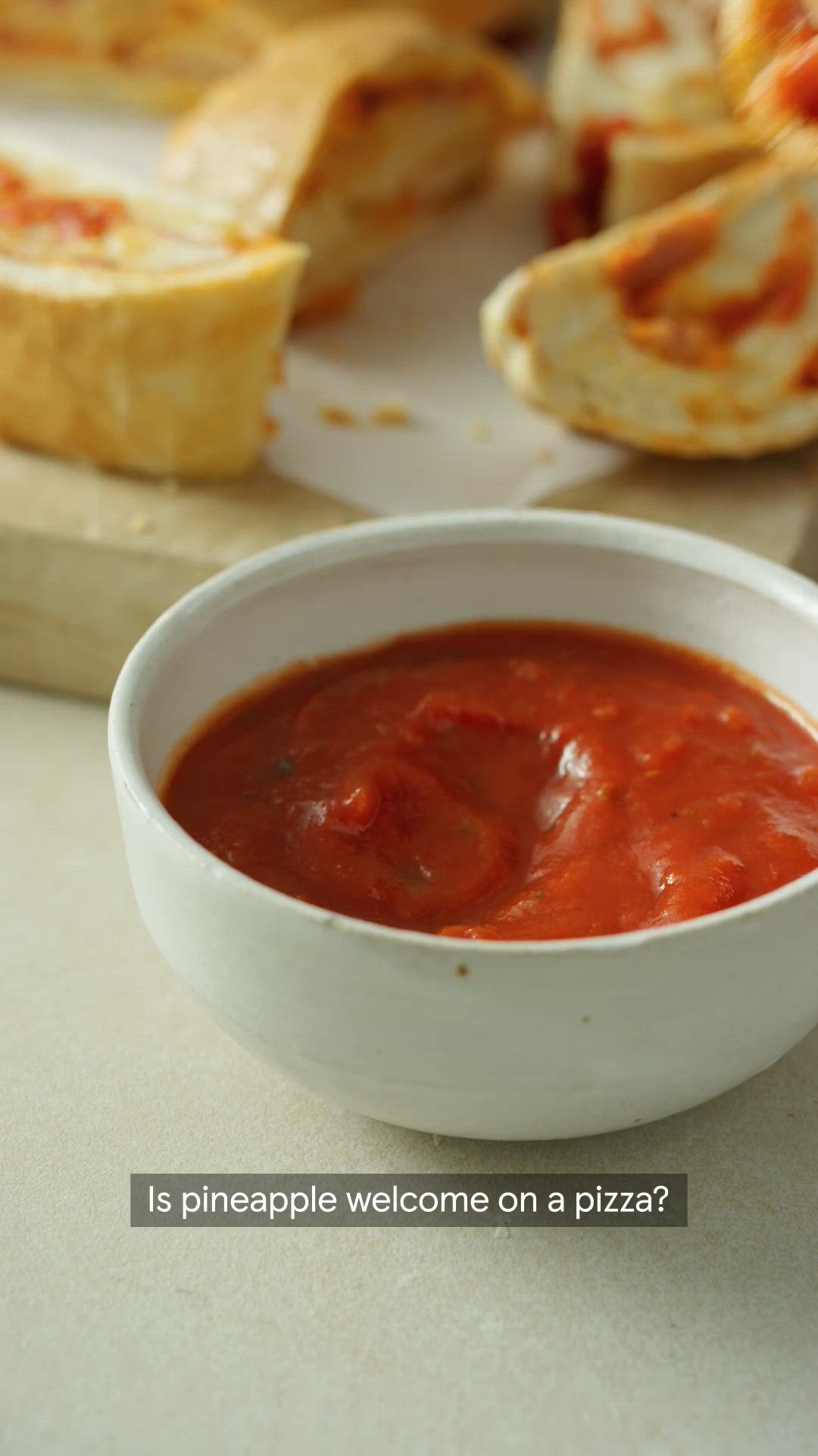 This may contain: a bowl of tomato sauce sitting on top of a counter next to some bread slices