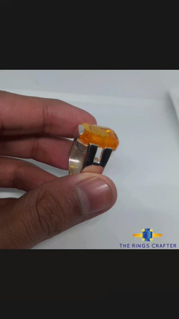 This may contain: an orange glass ring sitting on top of a clear display stand with a white background