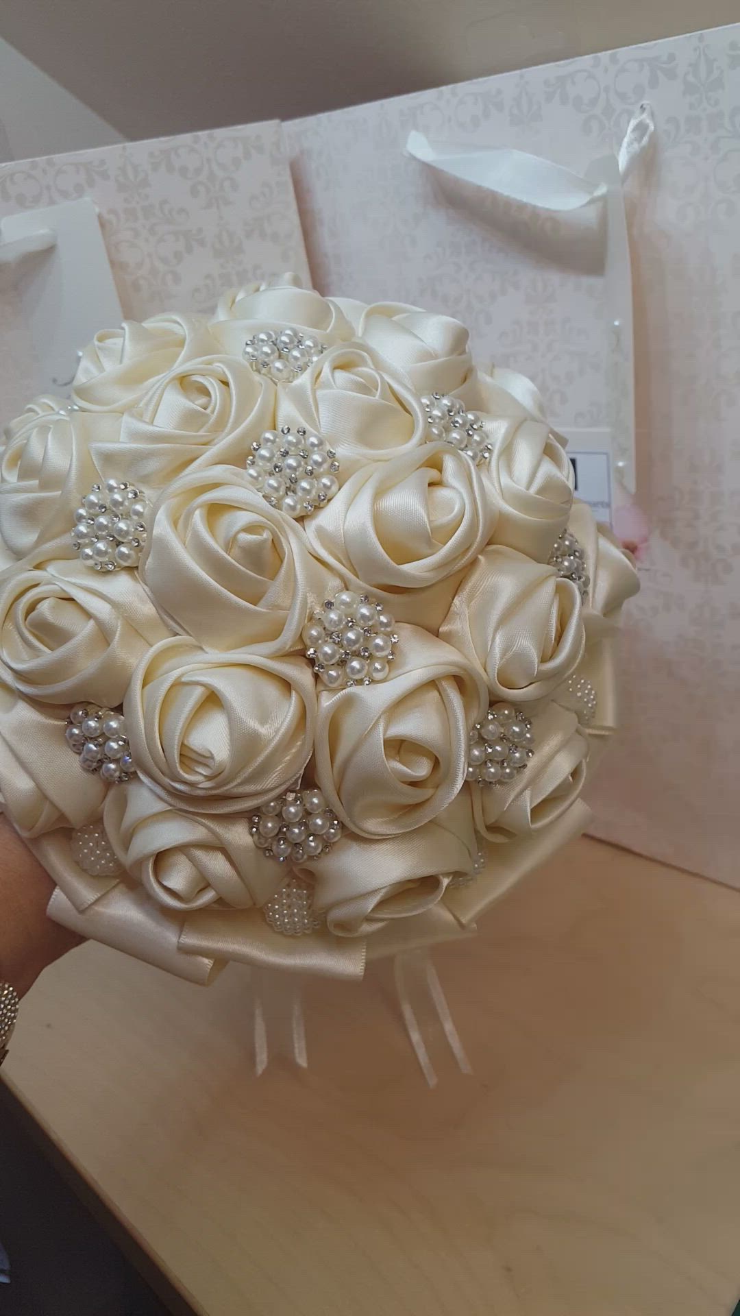 This may contain: a bridal bouquet is being held by a woman's hand on a table