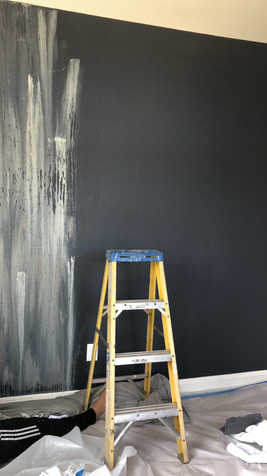 This may contain: two people sitting on a bed in front of a wall with black and white paint