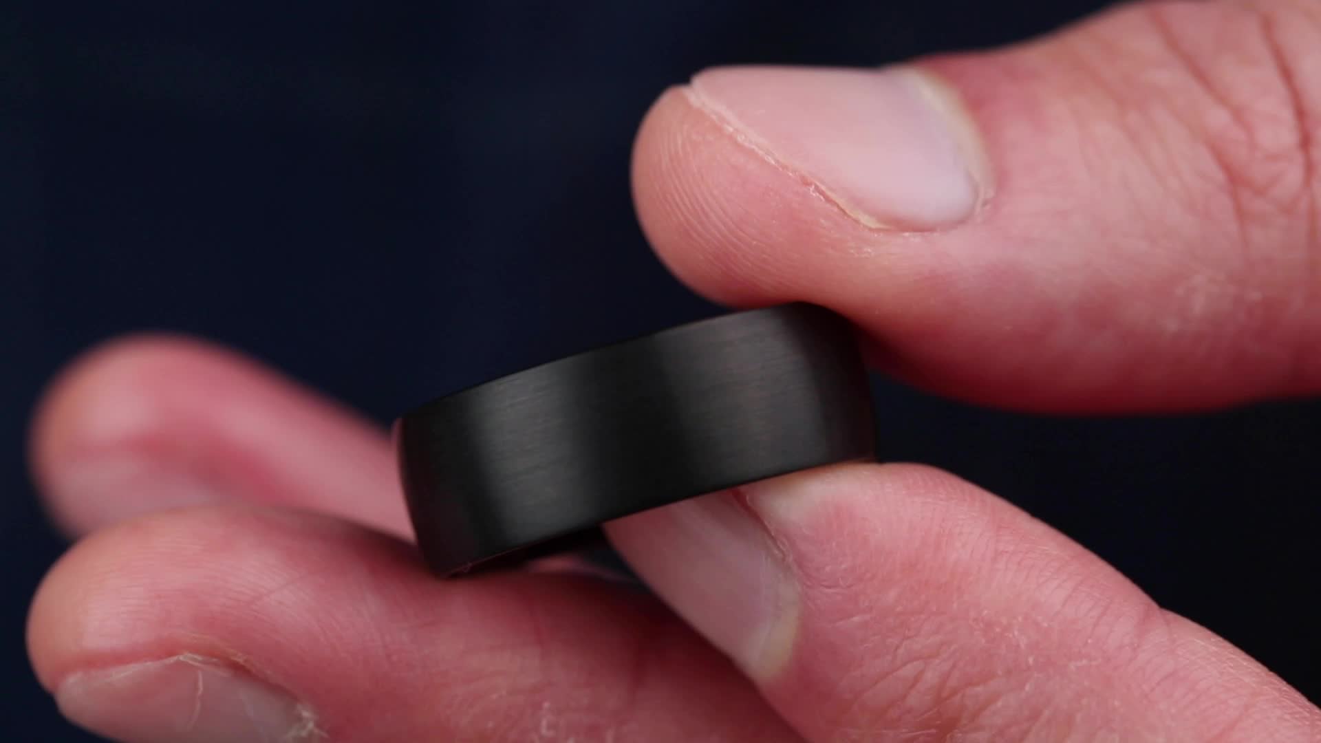 This may contain: a close up of a person's hand holding a black ring with one finger