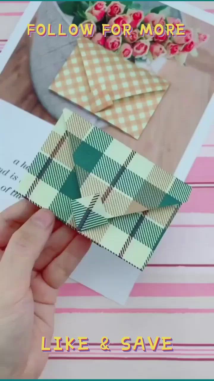 This may contain: someone is holding an origami box on top of some cards and envelopes