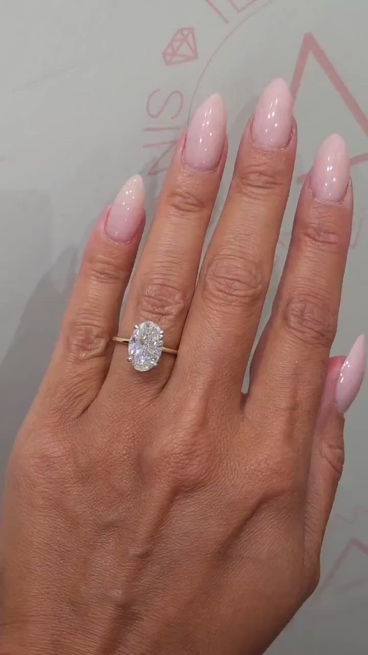 This may contain: a woman's hand with pink manicured nails and a diamond ring on it