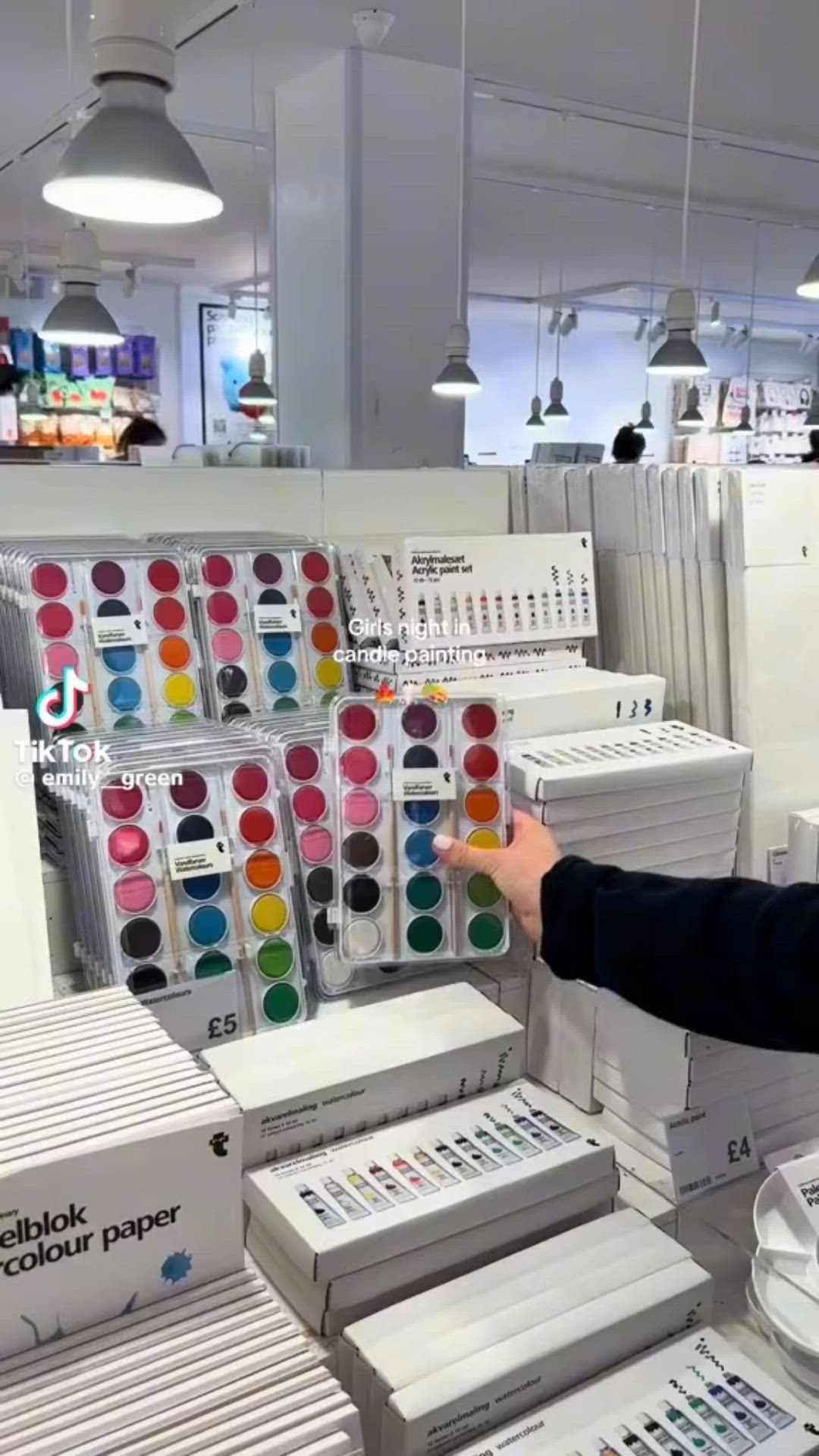 This may contain: a man standing in front of stacks of different colors of paint on display at a store