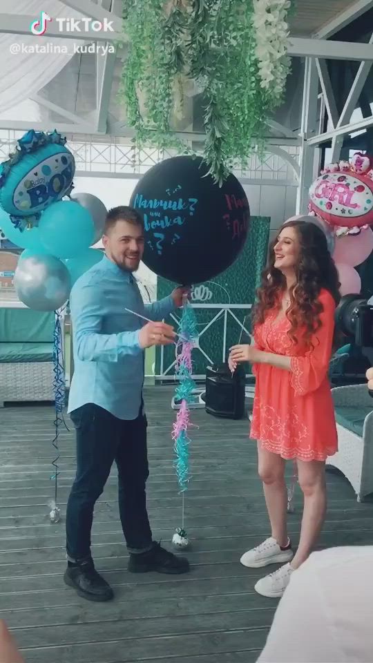 This may contain: a man and woman standing next to each other in front of balloons