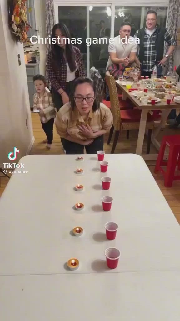 This may contain: a group of people standing around a table with cups on it and candles in the middle