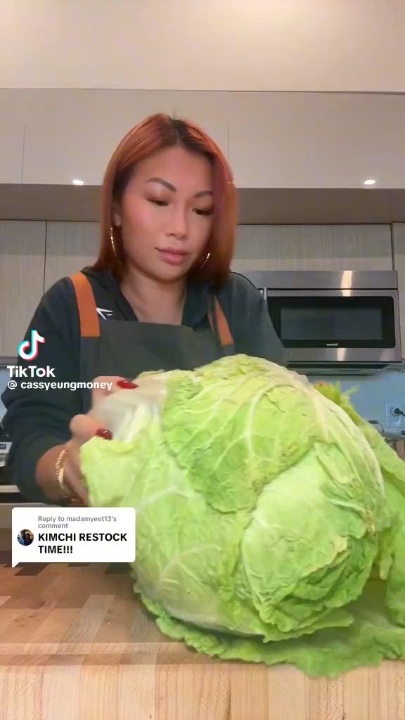 This may contain: a woman in an apron is cutting cabbage