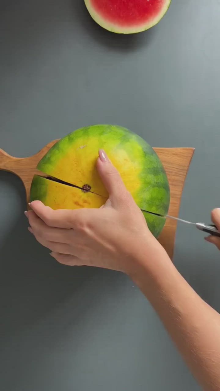 This may contain: a person is painting a watermelon on a wooden board with paint and scissors