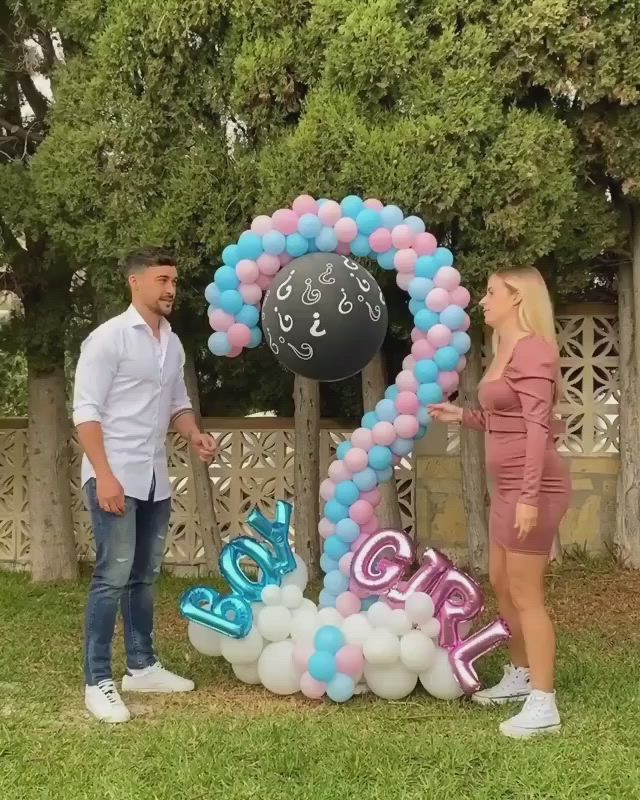 This may contain: two people standing in front of a balloon arch with the number twenty one on it