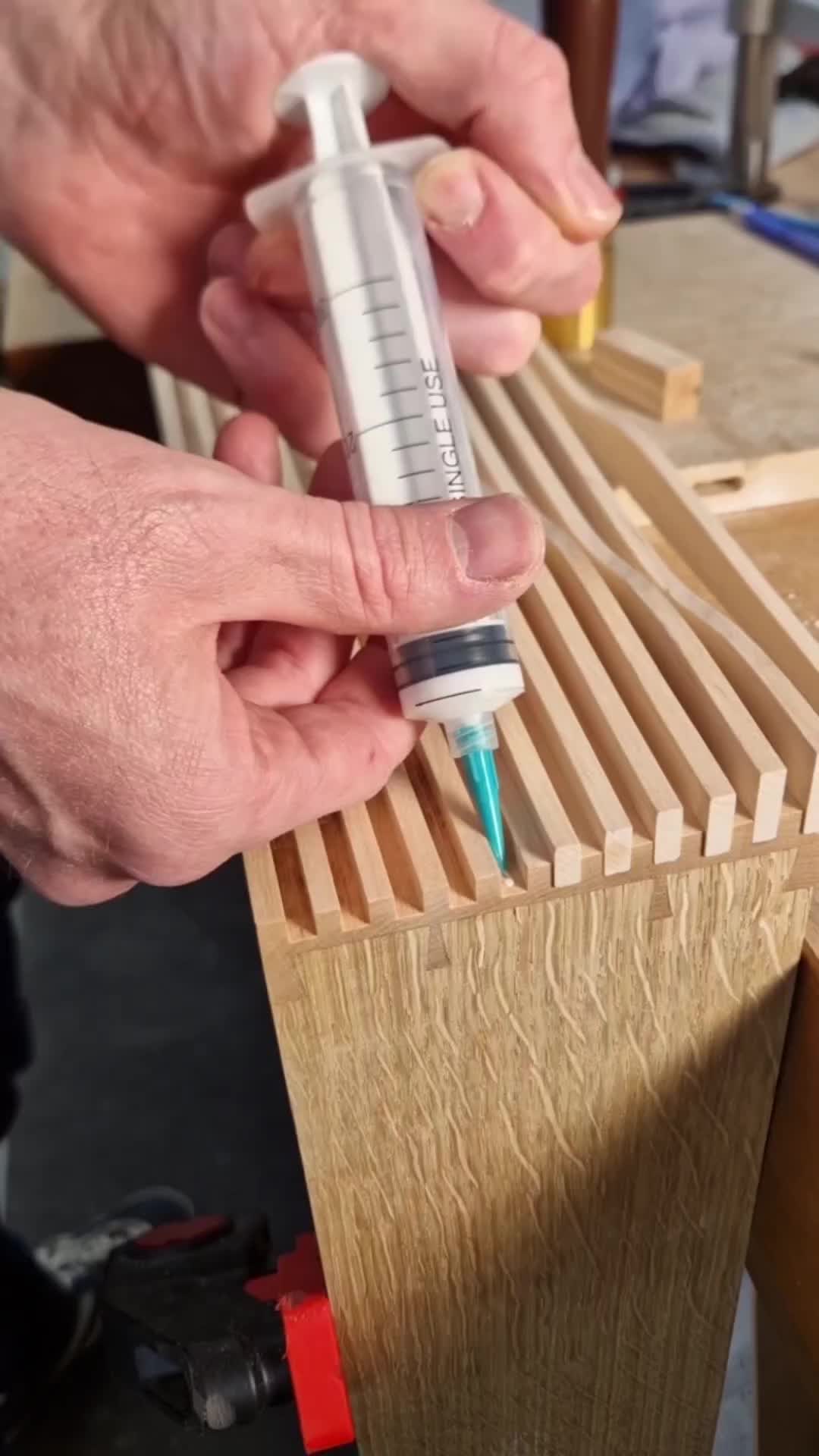 This may contain: two hands are working on a piece of wood with a syringe in it