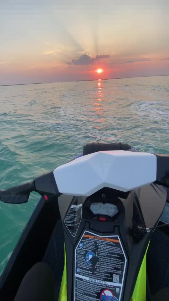 This may contain: the sun is setting over the ocean as seen from a motorboat in the water