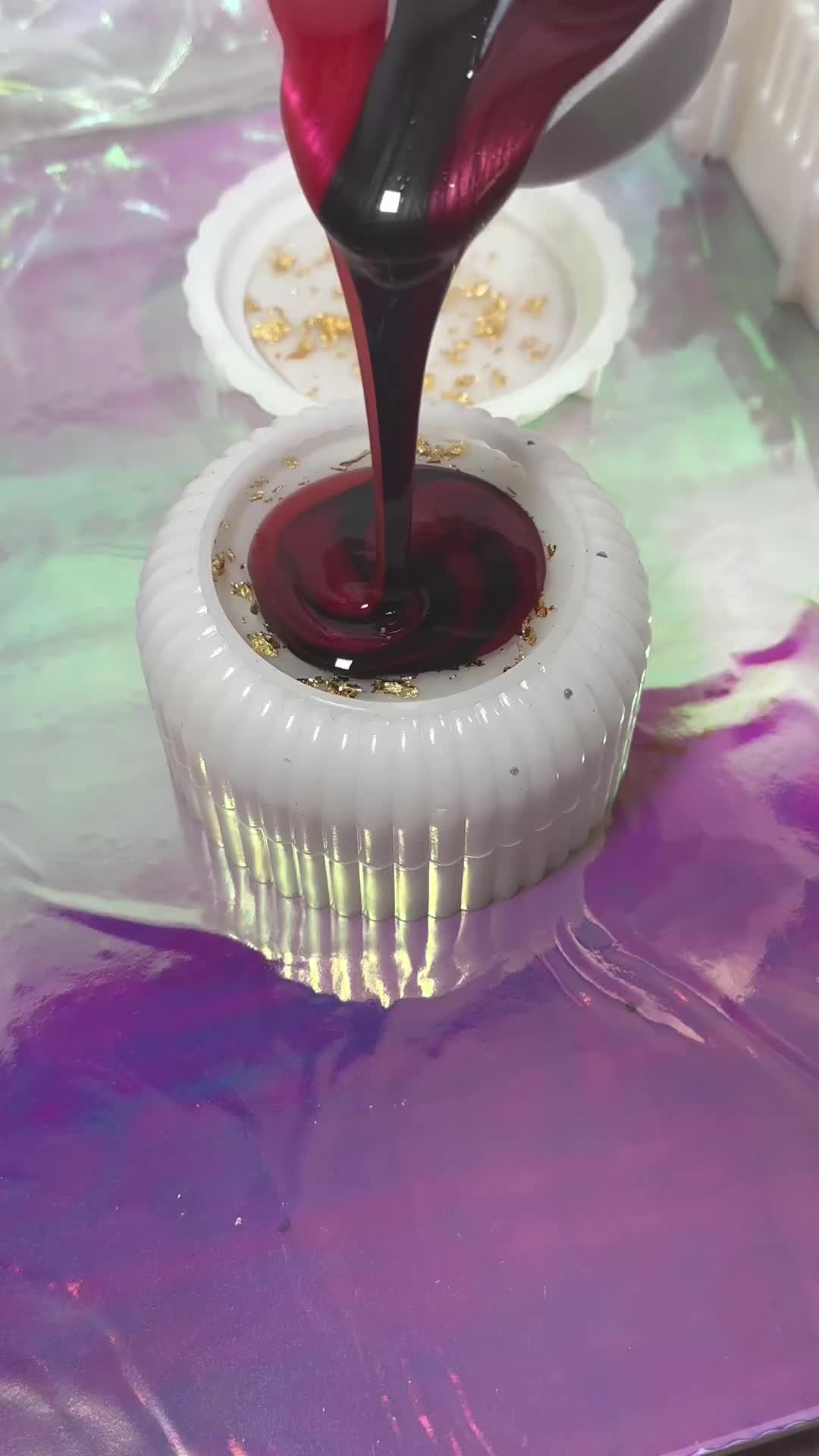 This may contain: a cupcake being filled with red liquid on top of a purple and white plate