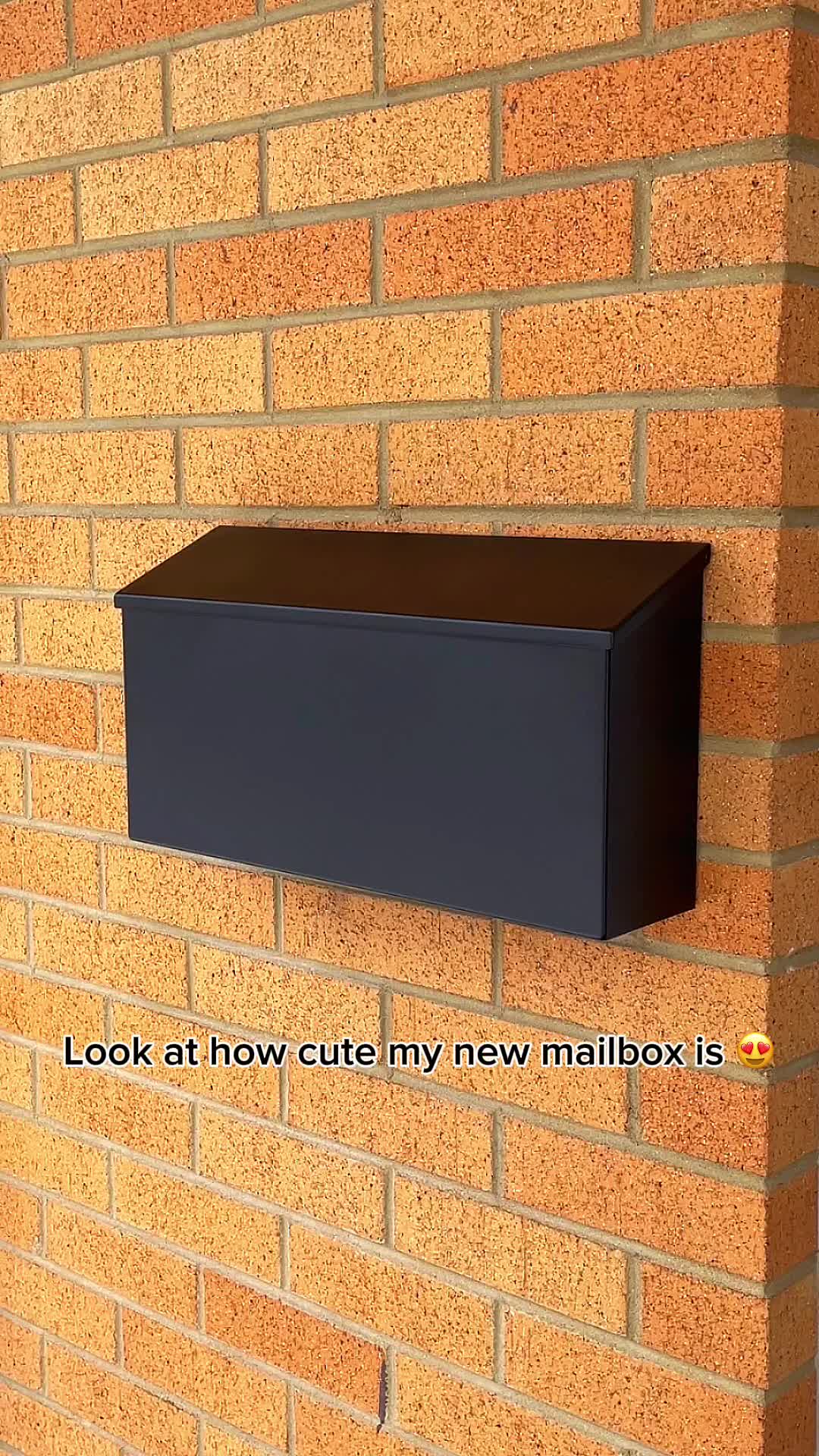 This may contain: a black mailbox mounted to the side of a brick wall with an inscription on it