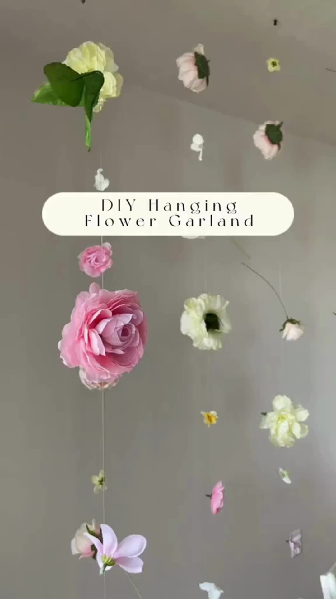 This may contain: pink and white flowers hanging from the ceiling with text overlay that reads diy floating flower garland