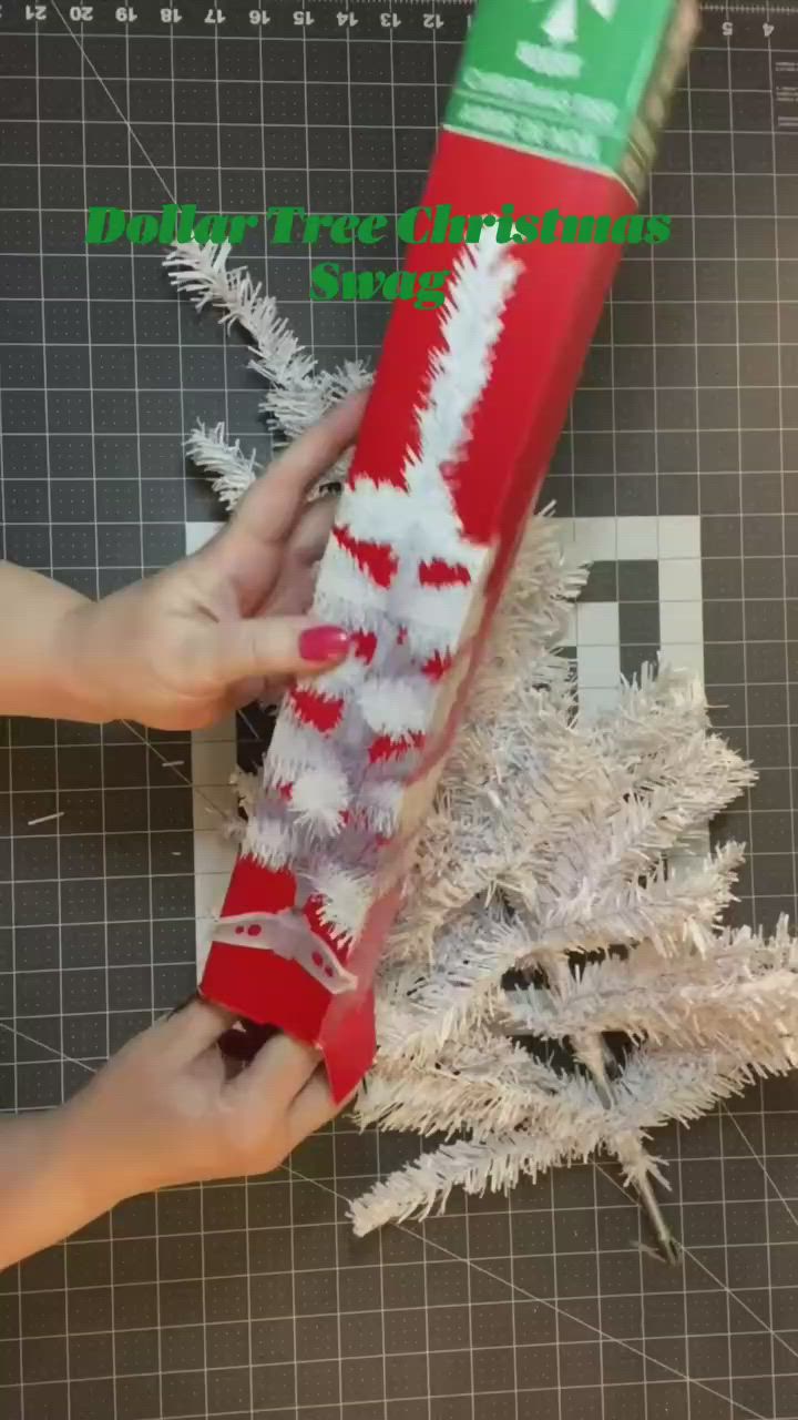 This may contain: someone is holding a red and white christmas cracker in front of a fake tree