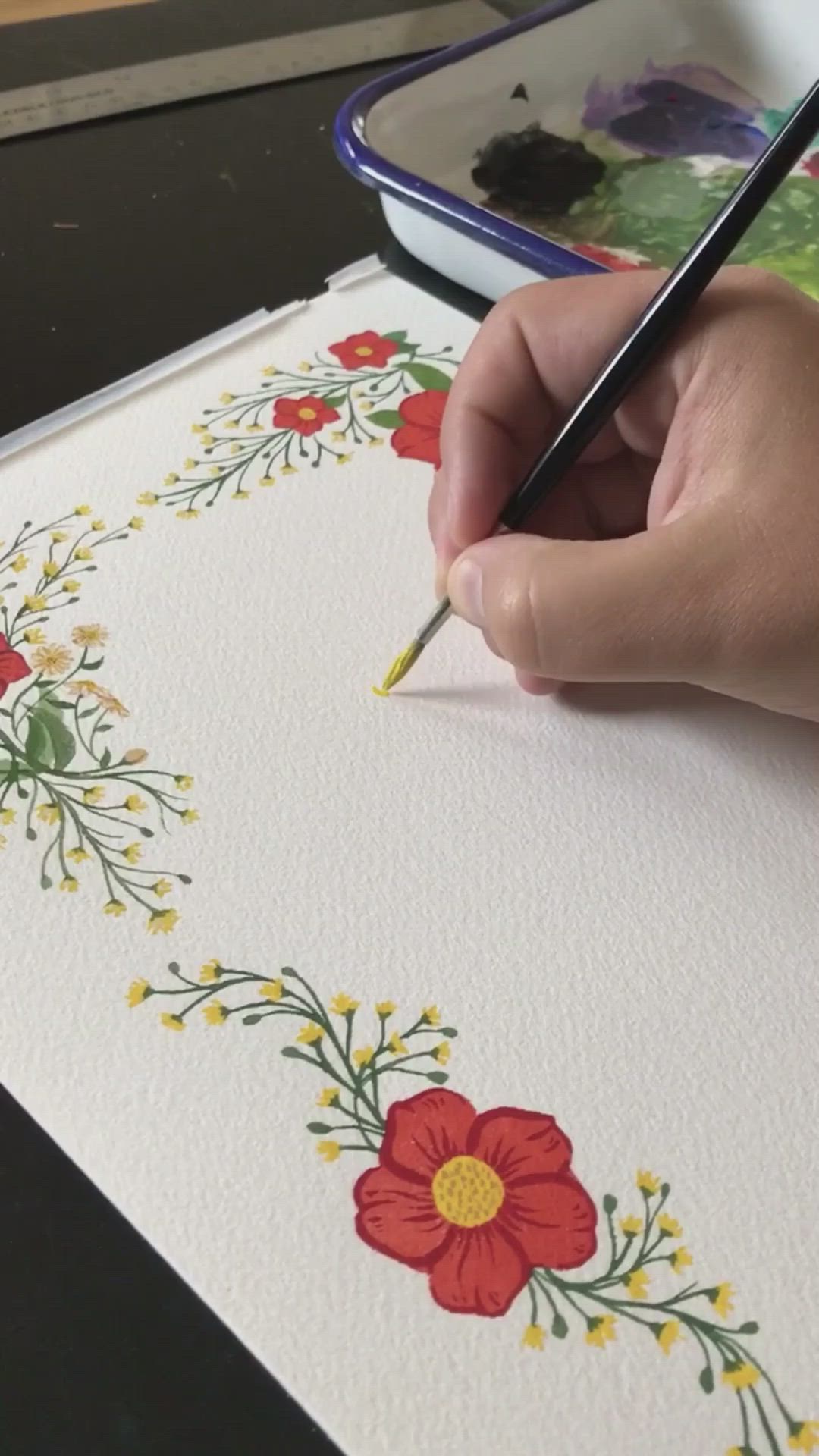 This may contain: a person is holding a pencil in their hand and painting flowers on paper with watercolors