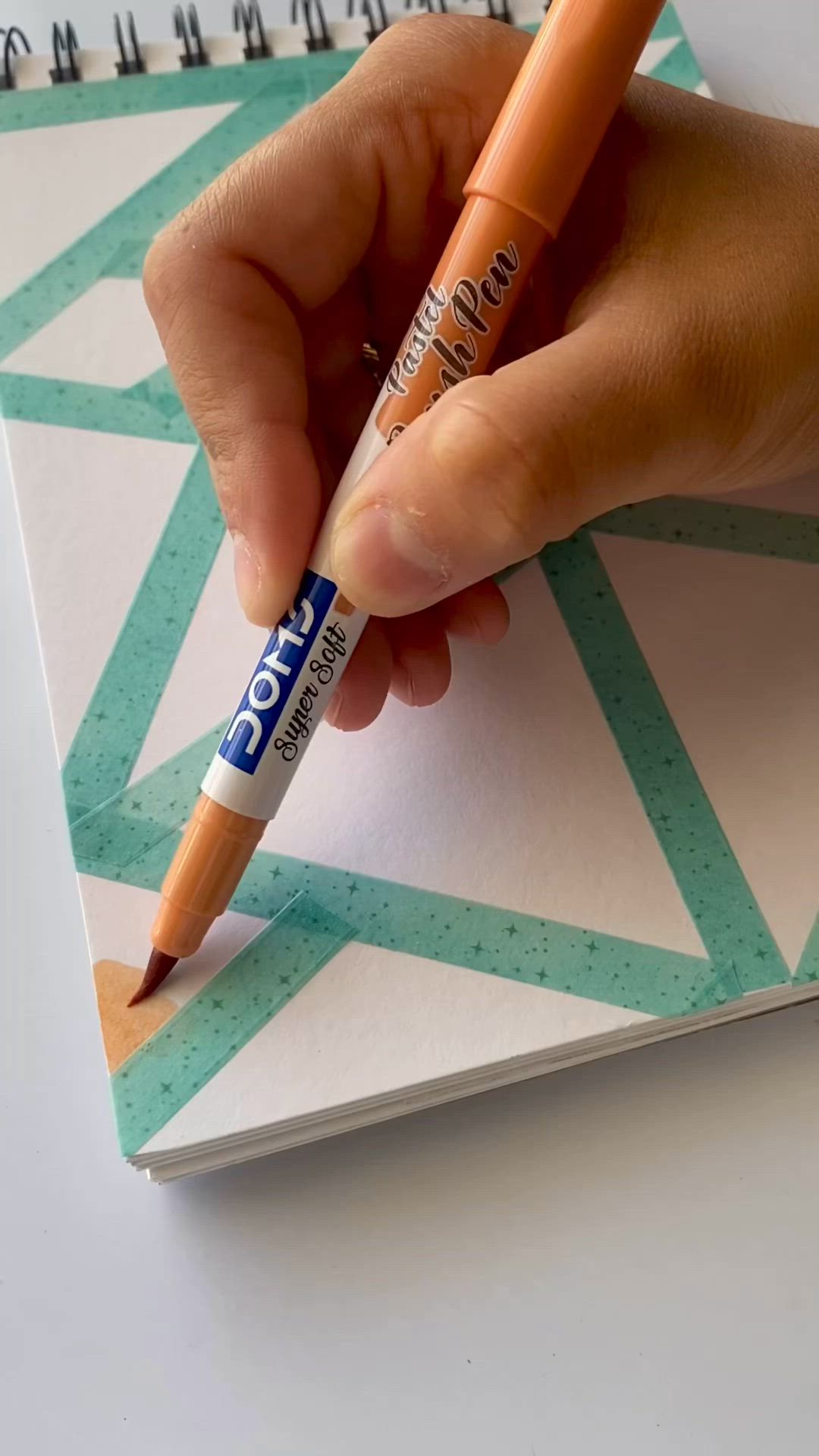 This may contain: a spiral notebook with colorful designs on it next to a potted plant and pencils