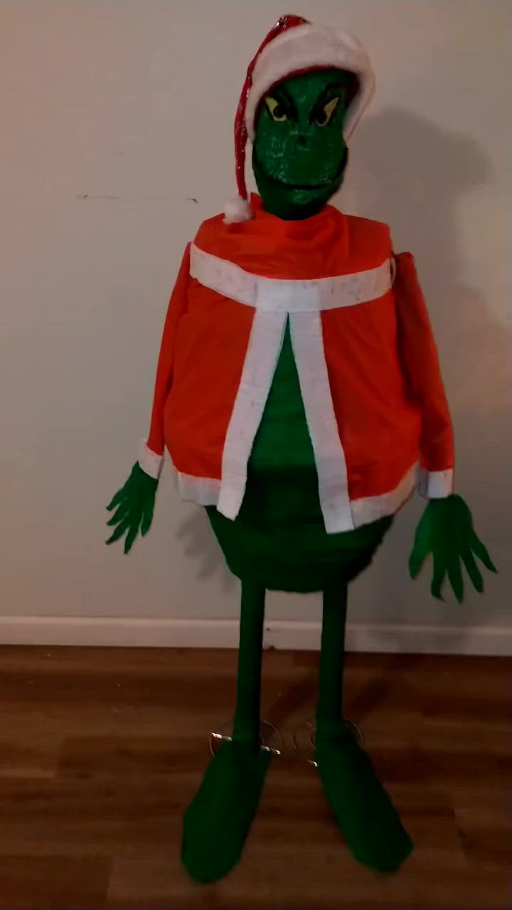 This may contain: an inflatable green man wearing a red and white outfit