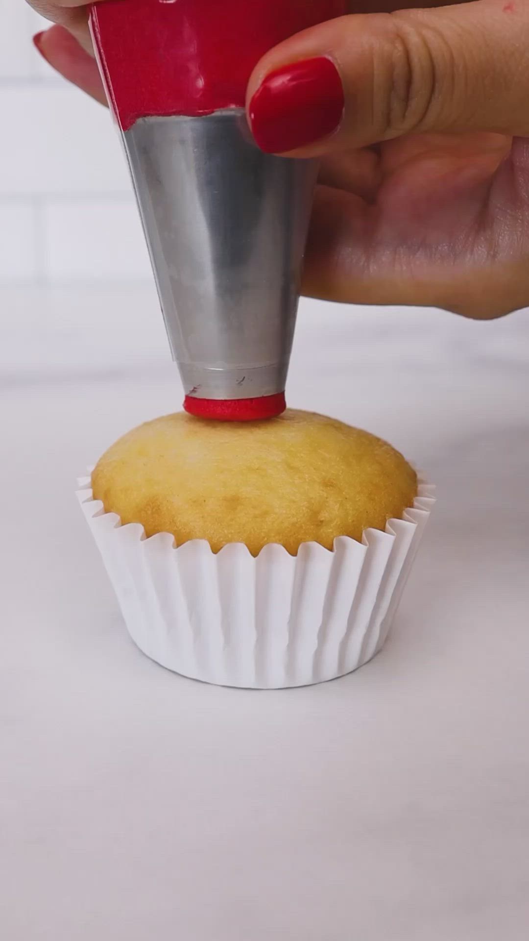 This may contain: someone is decorating a cupcake with green icing and red frosting on it