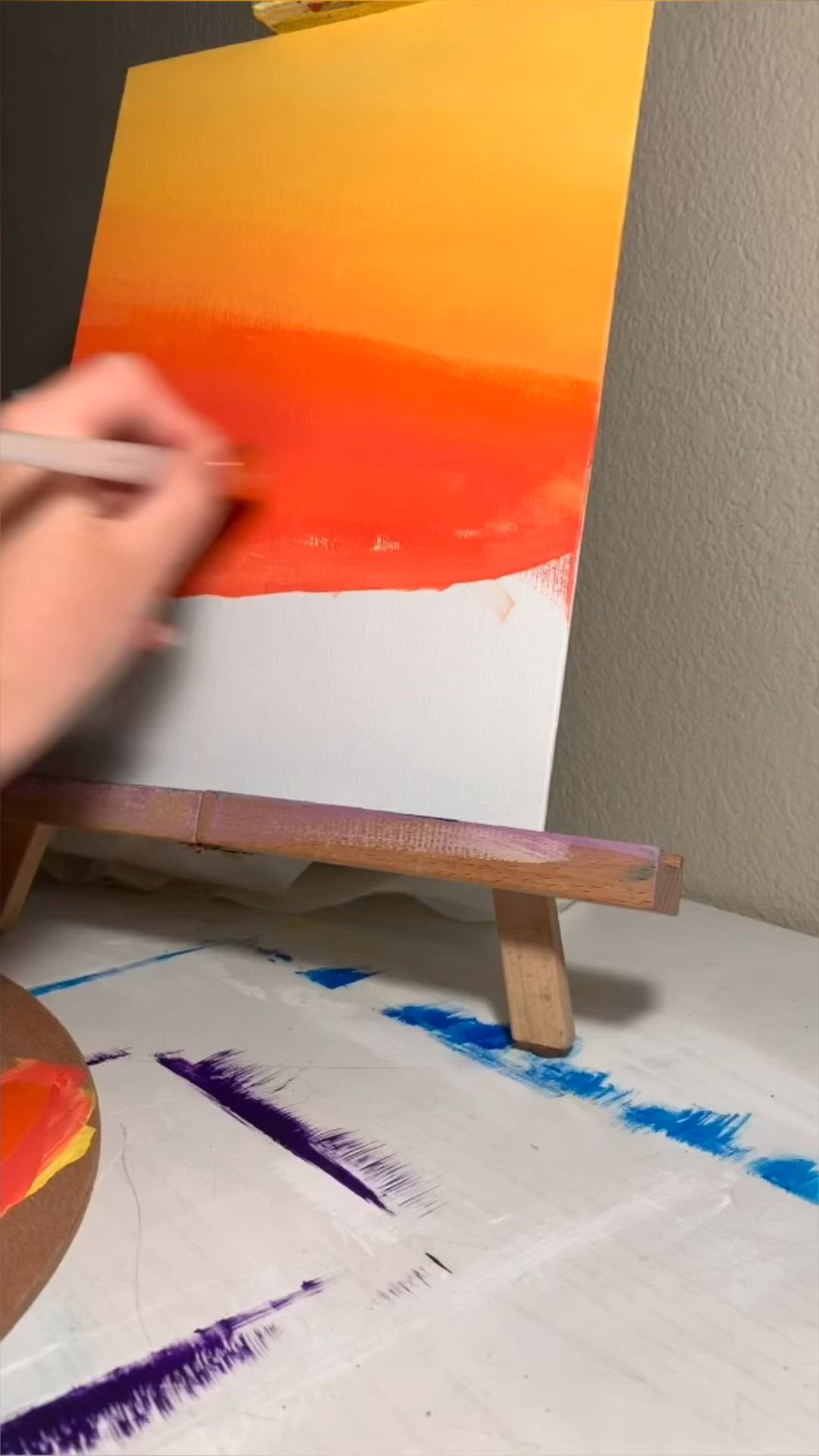 This may contain: a person is painting on an easel with a paintbrush in their left hand