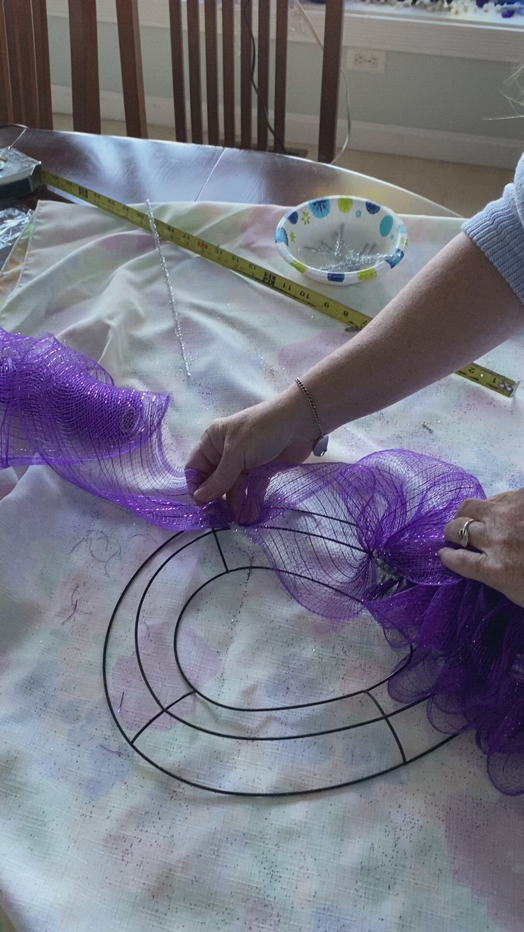 This may contain: a woman is working on something with purple fabric and scissors at the table in front of her