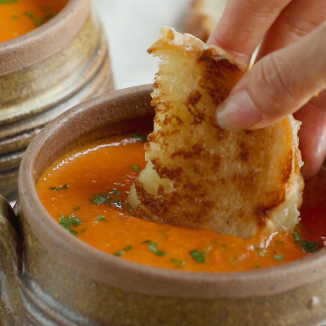 This may contain: a person dipping some bread into a bowl of soup