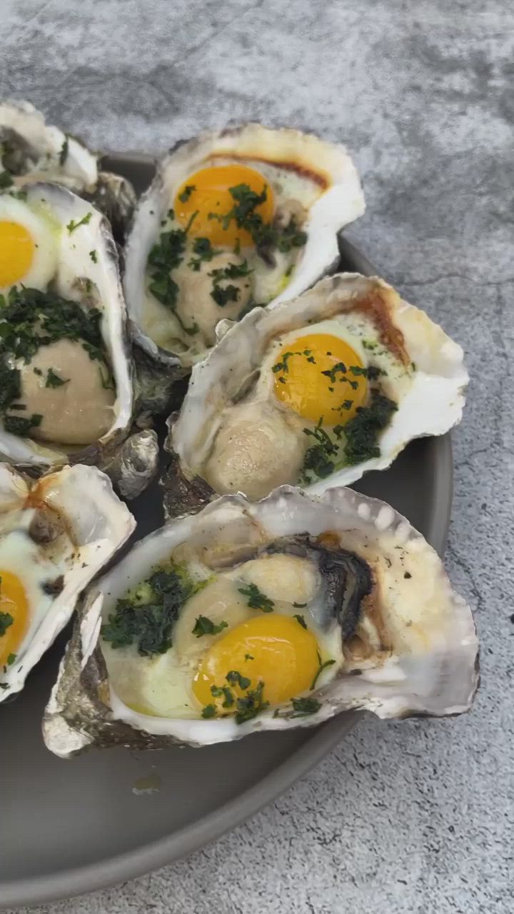 This may contain: several oysters on a plate with an egg in the middle