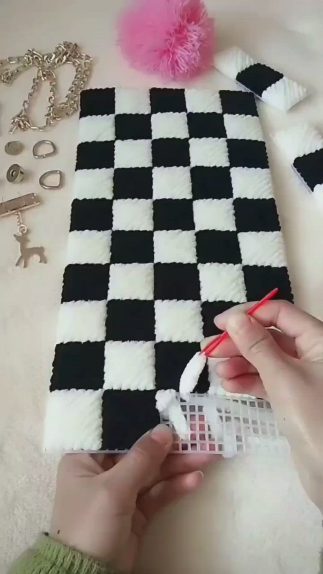 This may contain: someone is making a black and white checkered rug with pom - poms