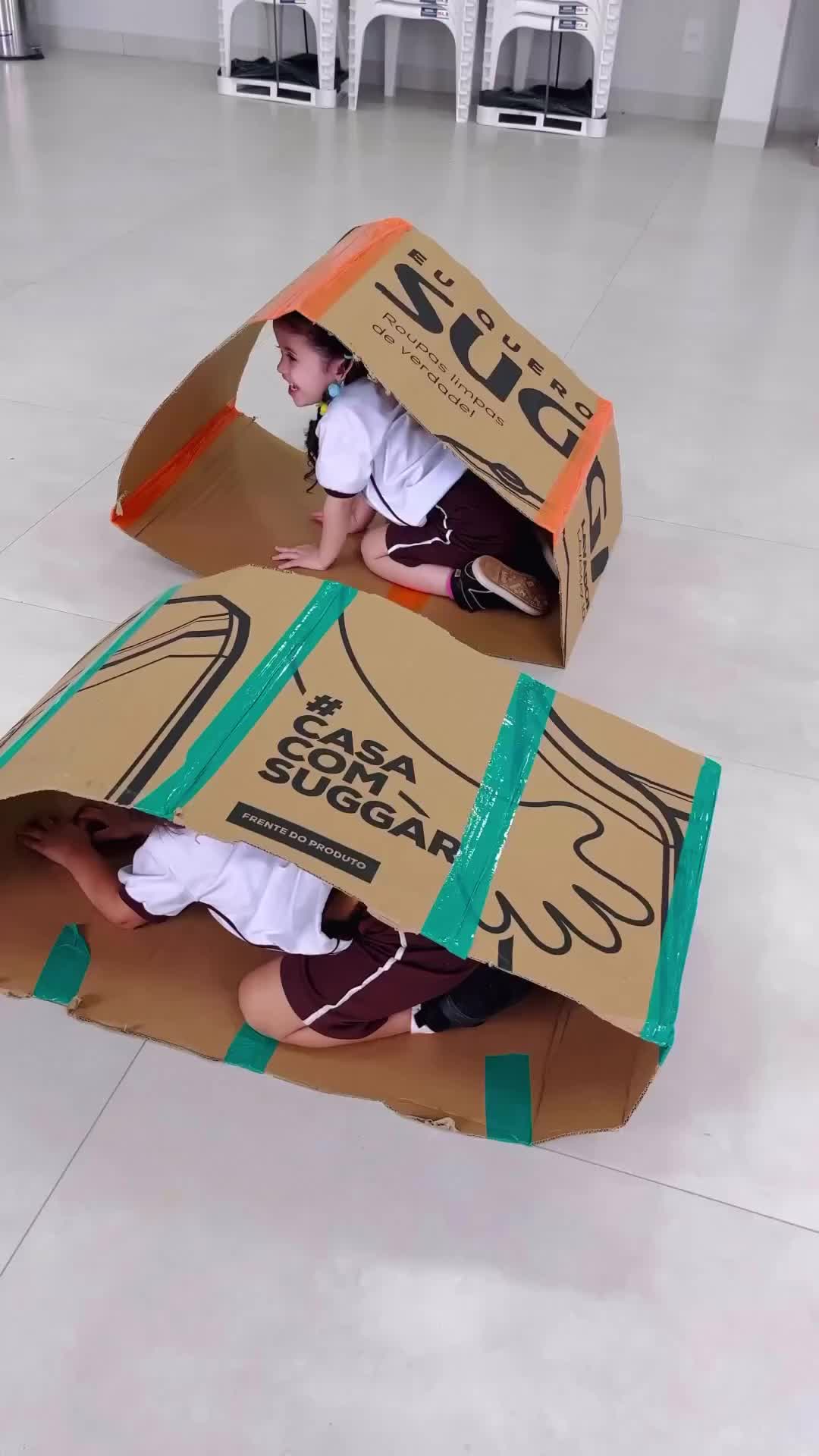 This may contain: two children are playing with cardboard boxes on the floor