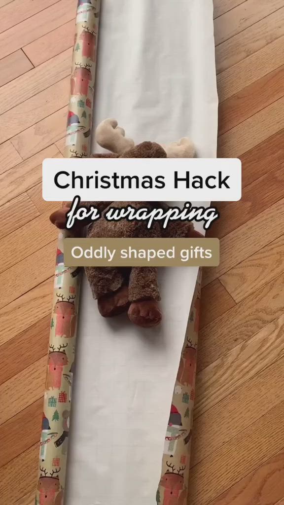 This may contain: someone wrapping christmas presents on a sheet of paper with the words, christmas hack for wrapping oddly shaped gifts