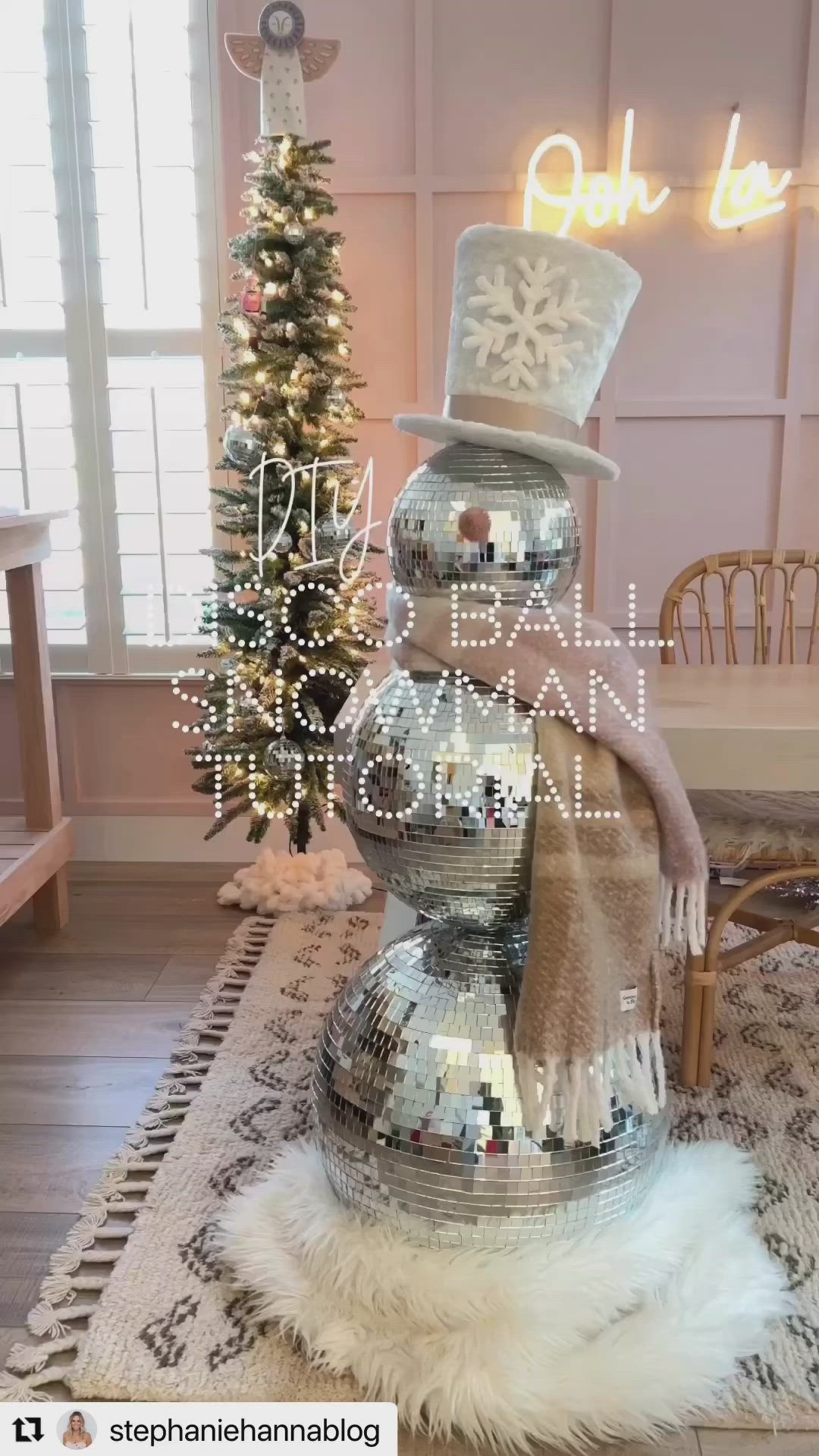 This may contain: a snowman made out of disco balls on top of a rug next to a christmas tree