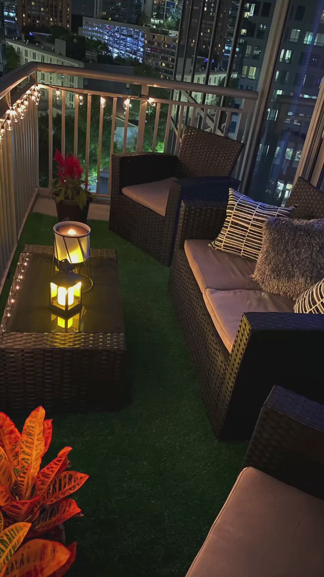 This may contain: an outdoor living area with wicker furniture and string lights on the balcony at night