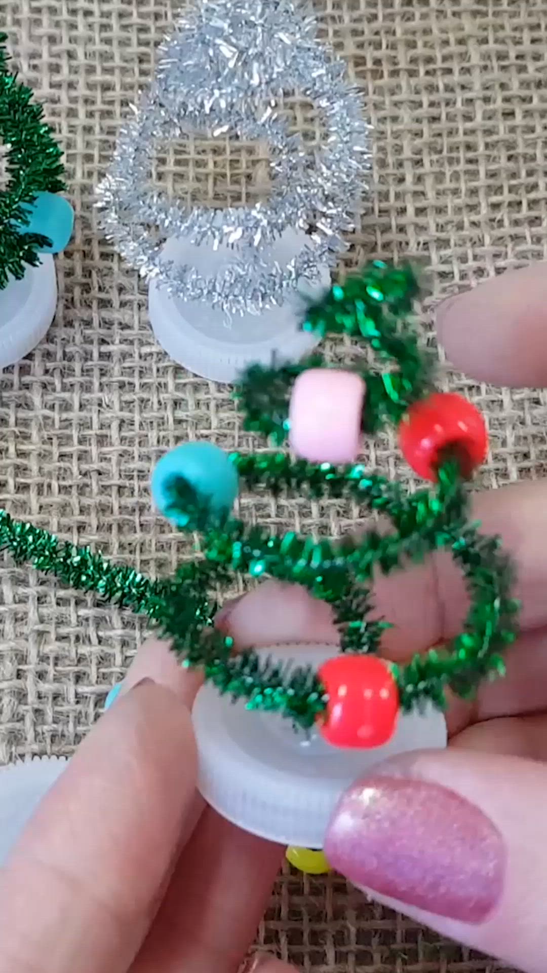 This may contain: someone is making christmas wreaths out of plastic beads and tinsel on the table