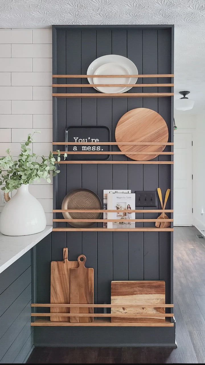 This may contain: the shelves in this kitchen are organized with wooden cutting boards, plates and utensils