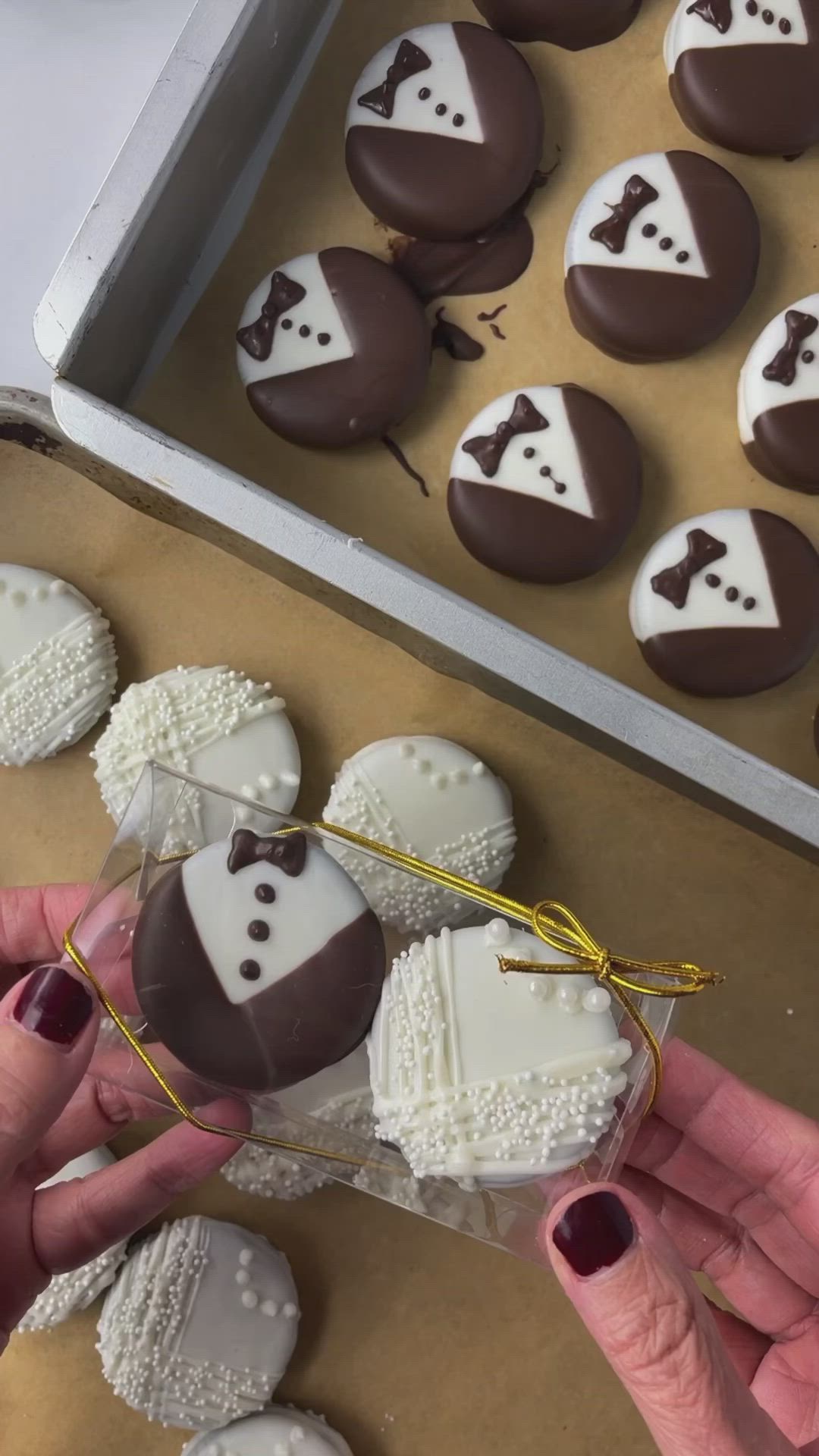 This may contain: a person holding a chocolate covered heart and bow tie cookie in front of other cookies