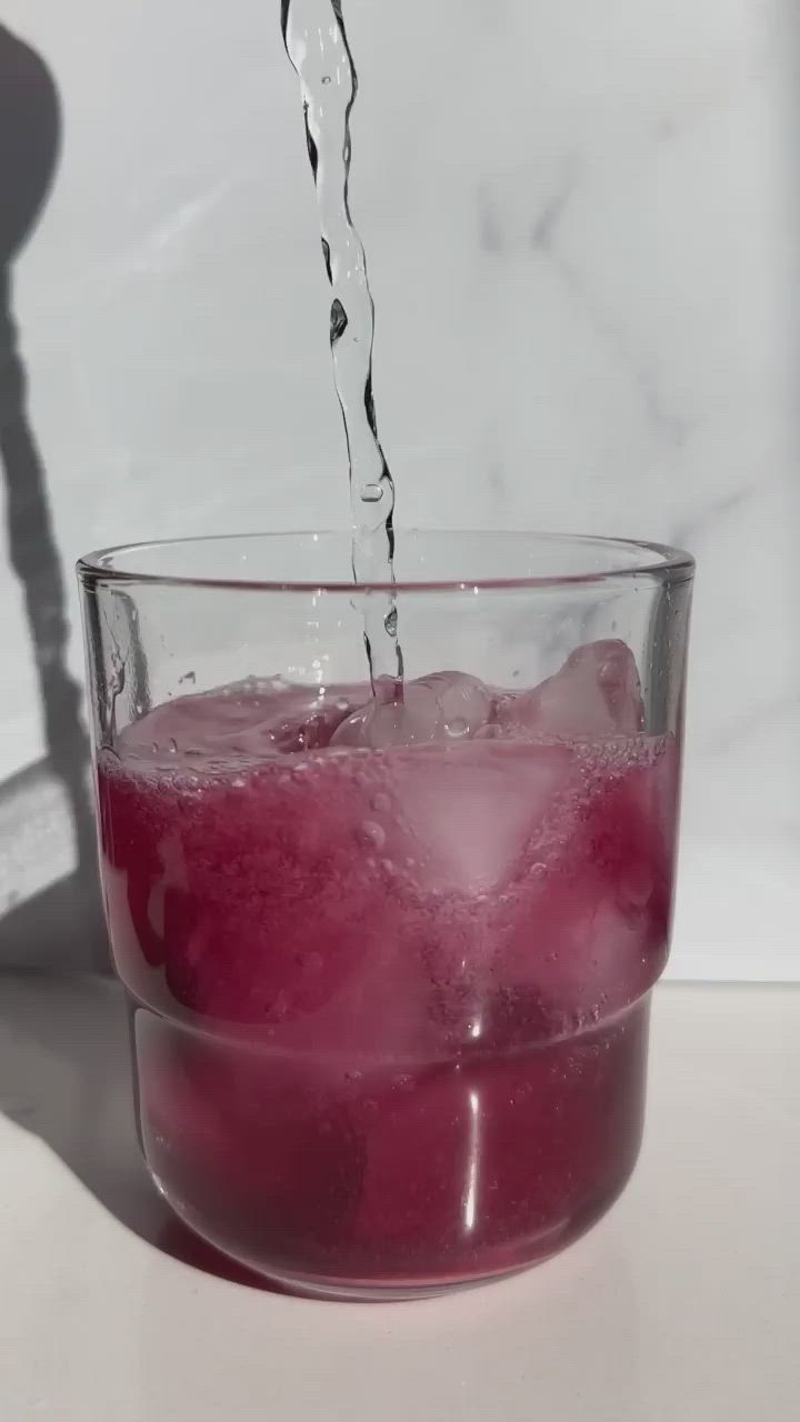 This may contain: a red drink with rosemary garnish on the rim and text sparkling blueberry ginger cocktail