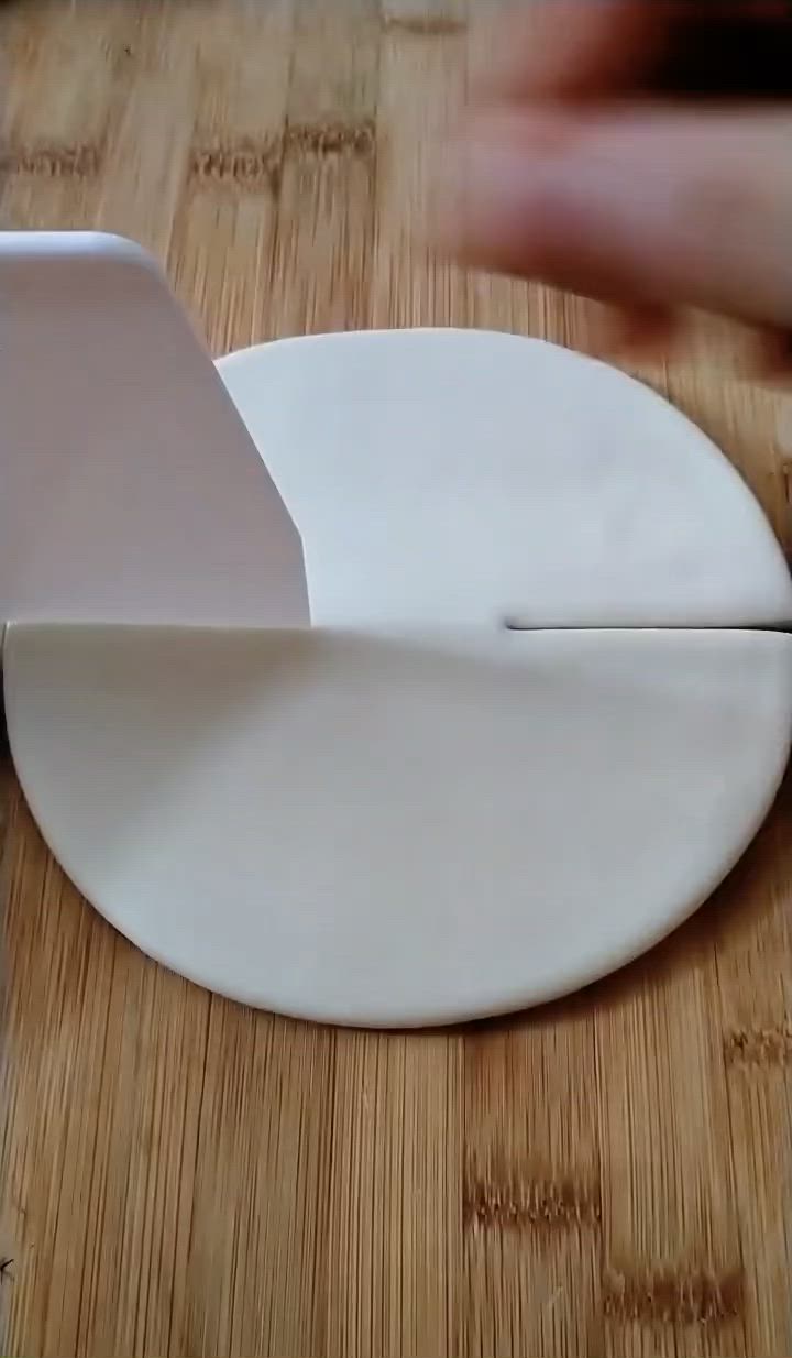 This may contain: a person cutting into a piece of paper on top of a wooden table