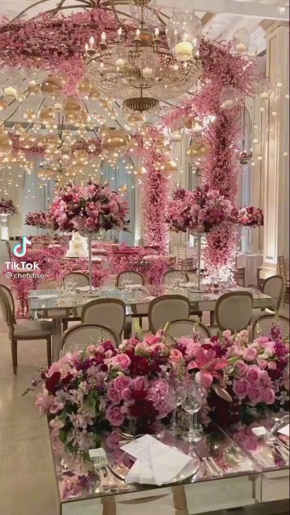 This may contain: a dining room with pink flowers and chandeliers