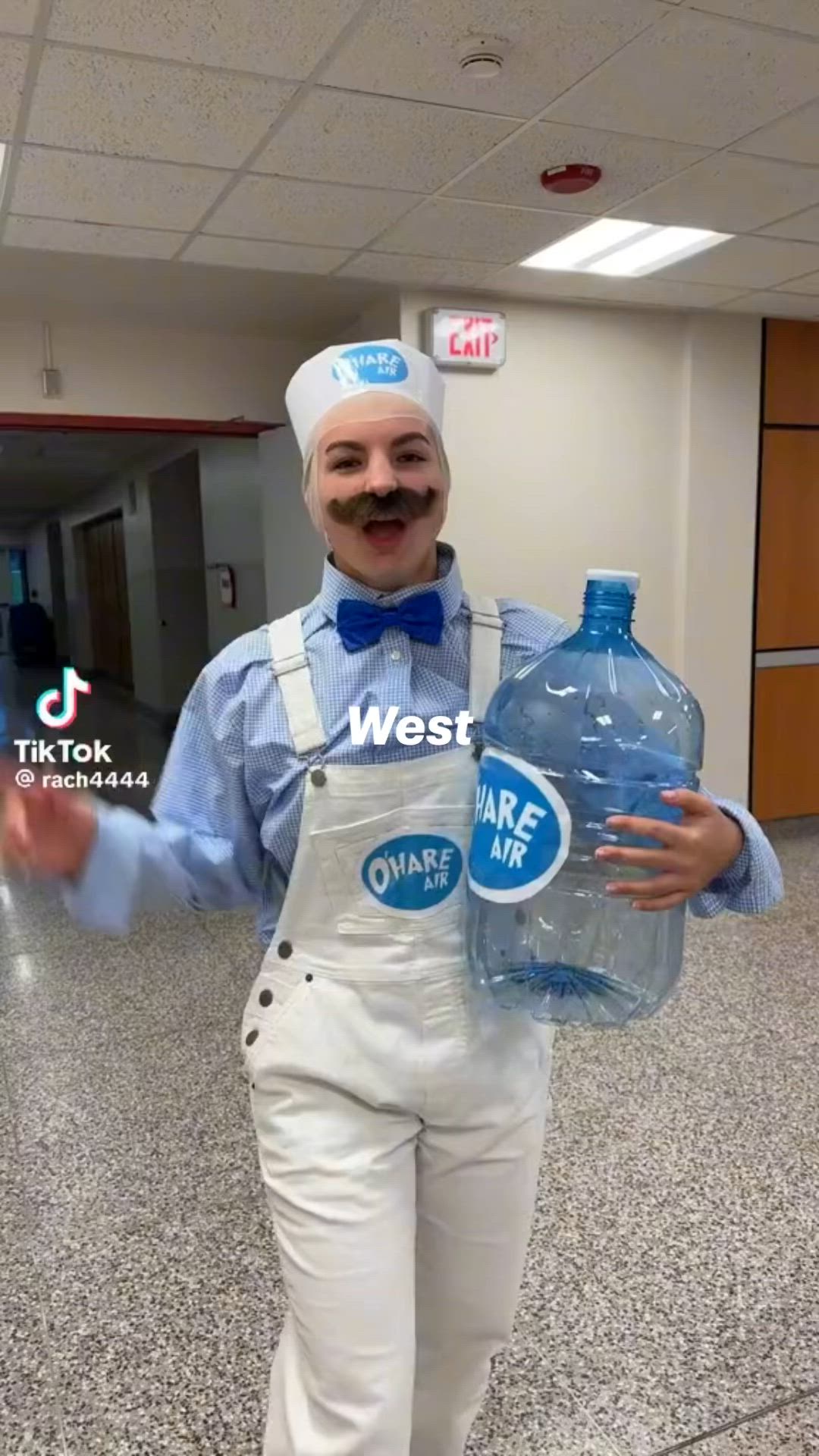 This may contain: a man dressed in white overalls and a blue shirt is holding two water bottles