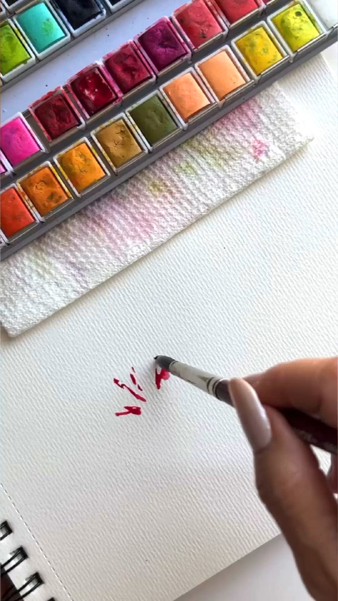 This may contain: a pink flower painted on white paper next to a brush