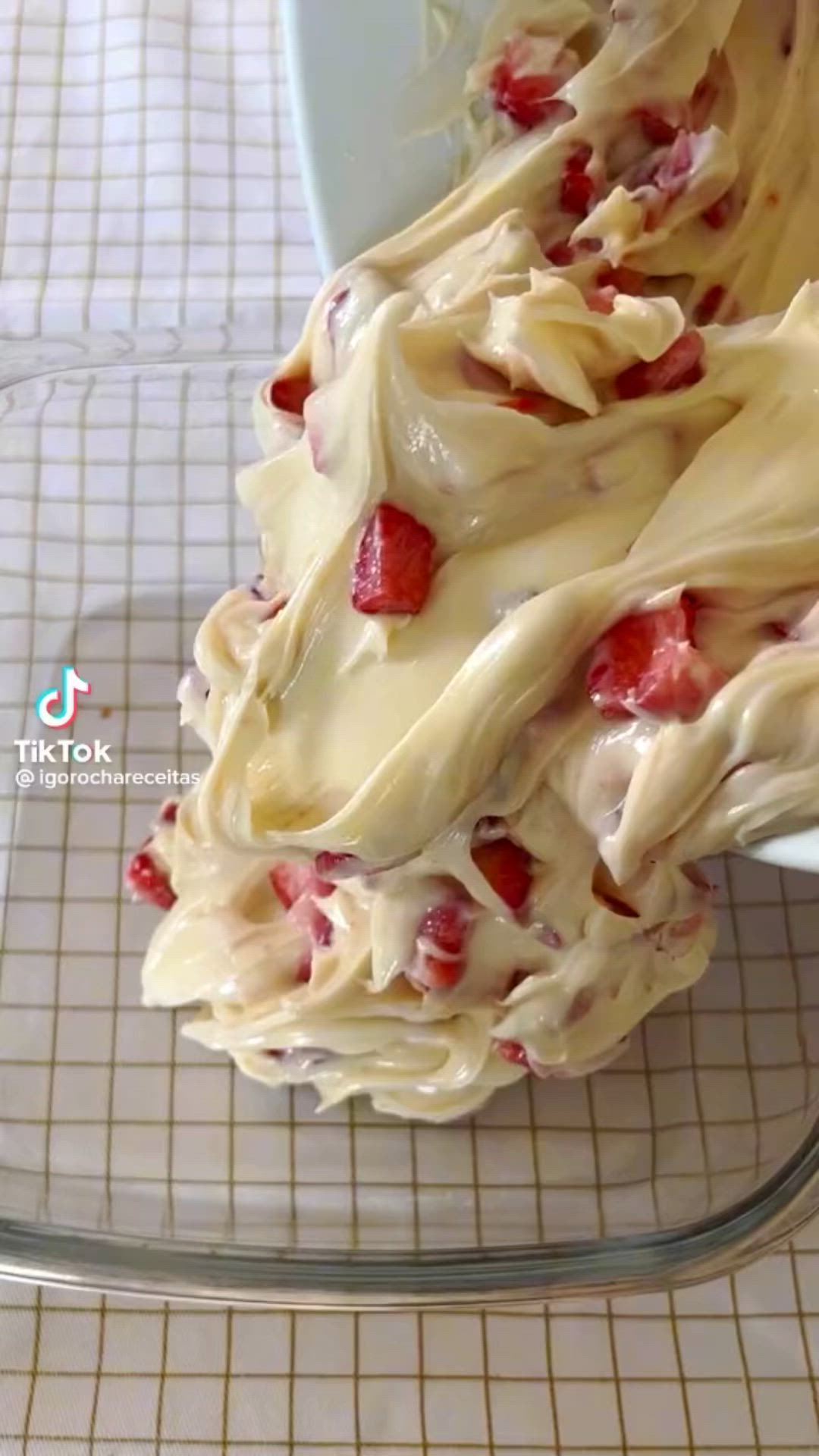 This may contain: a bowl filled with cream and strawberries on top of a table