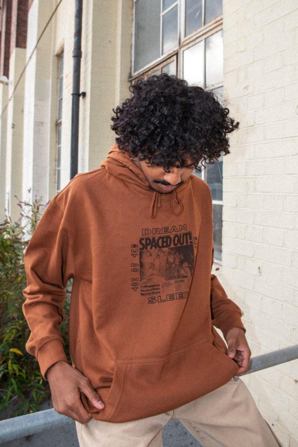 This contains: a man with curly hair wearing a brown hoodie