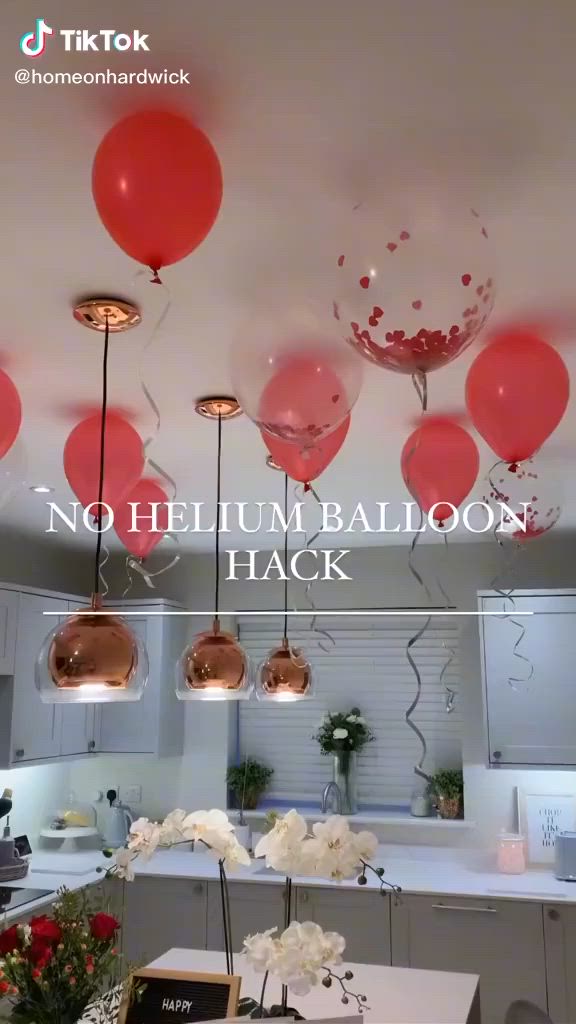 This may contain: a kitchen with balloons hanging from the ceiling and flowers in vases on the counter