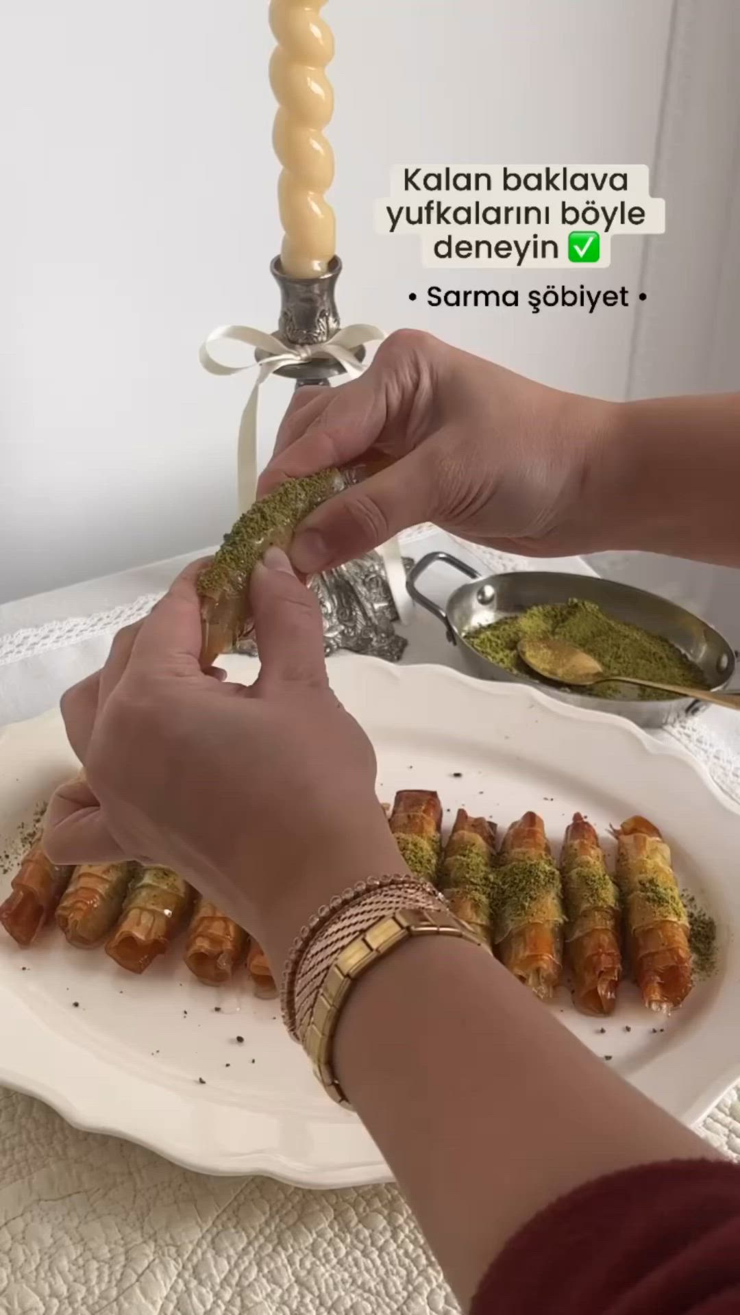 This may contain: a woman is serving food on a white plate with a candle in the background and another person's hand reaching for it