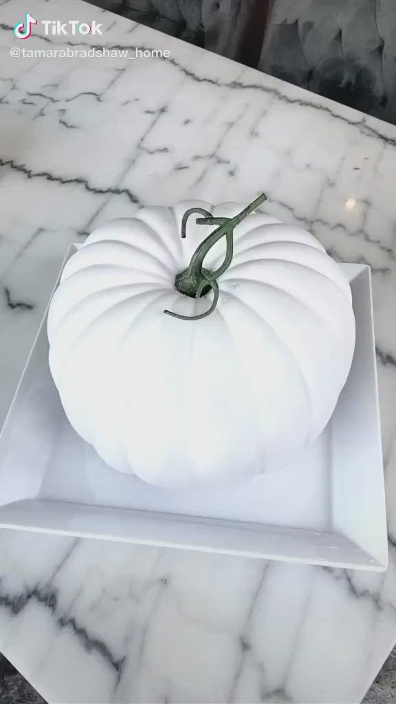 This may contain: a white pumpkin sitting on top of a counter next to some silver glittered decorations