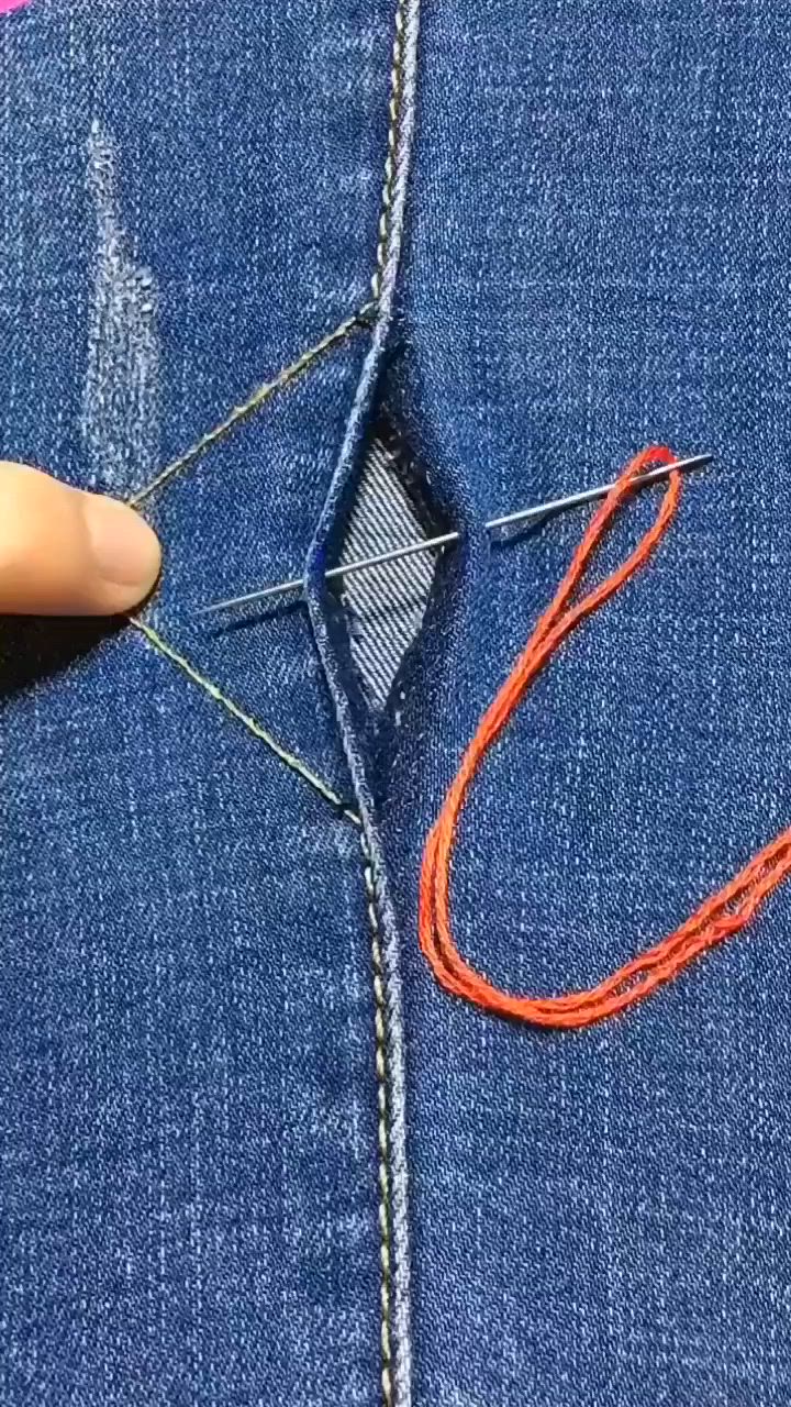 This may contain: someone is stitching an orange string into the back pocket of a pair of jeans